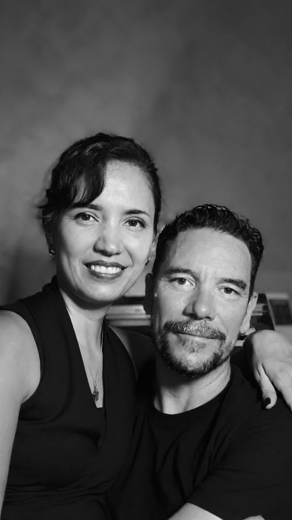 Retrato em preto e branco de Clau e Marina, sorrindo, lado a lado.